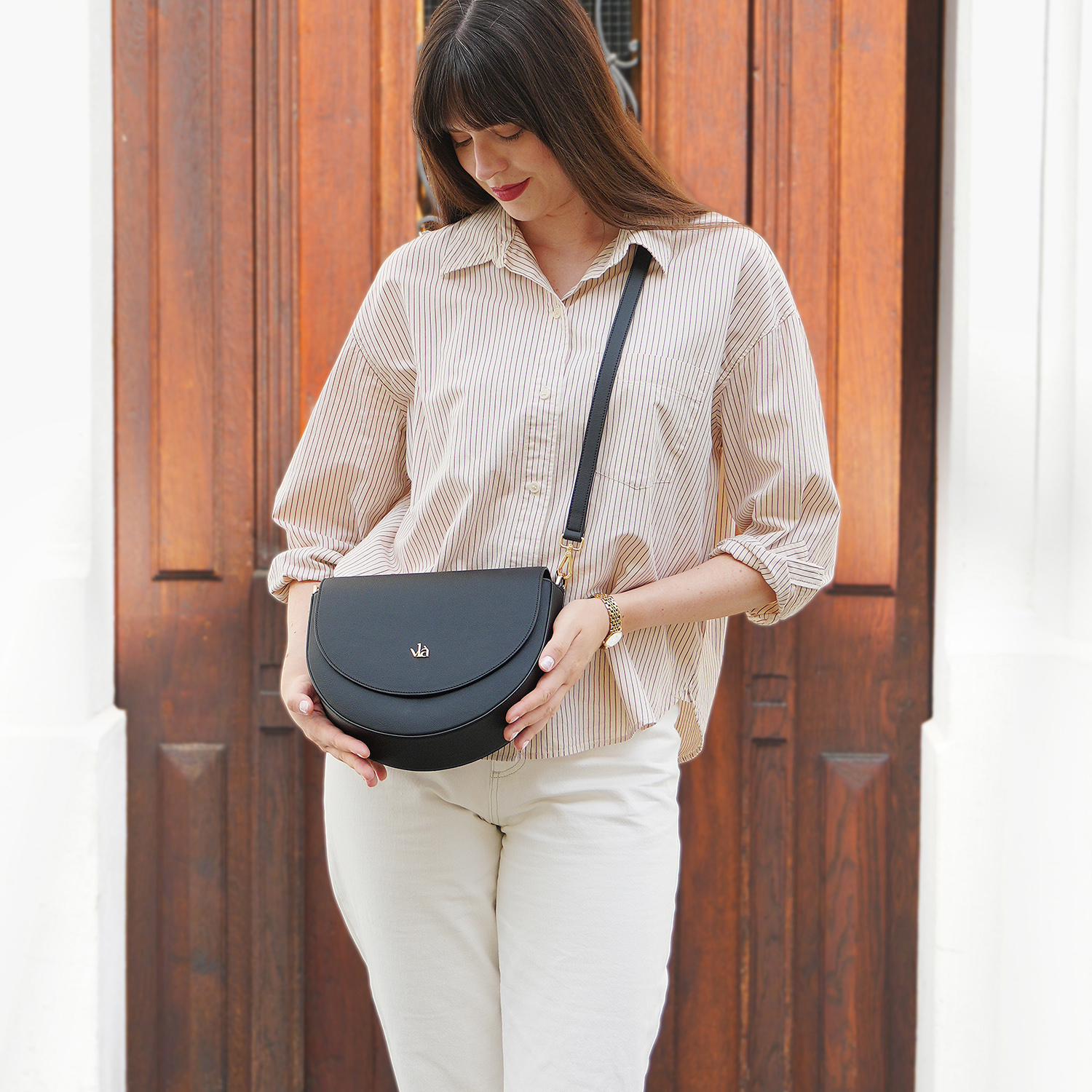 vlà Alice Halbmond-Tasche mit Model vor einer Tür