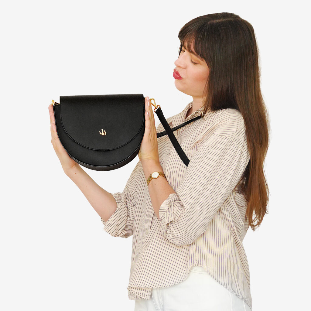vlà Alice Half Moon Bag in Schwarz – in der Hand getragen